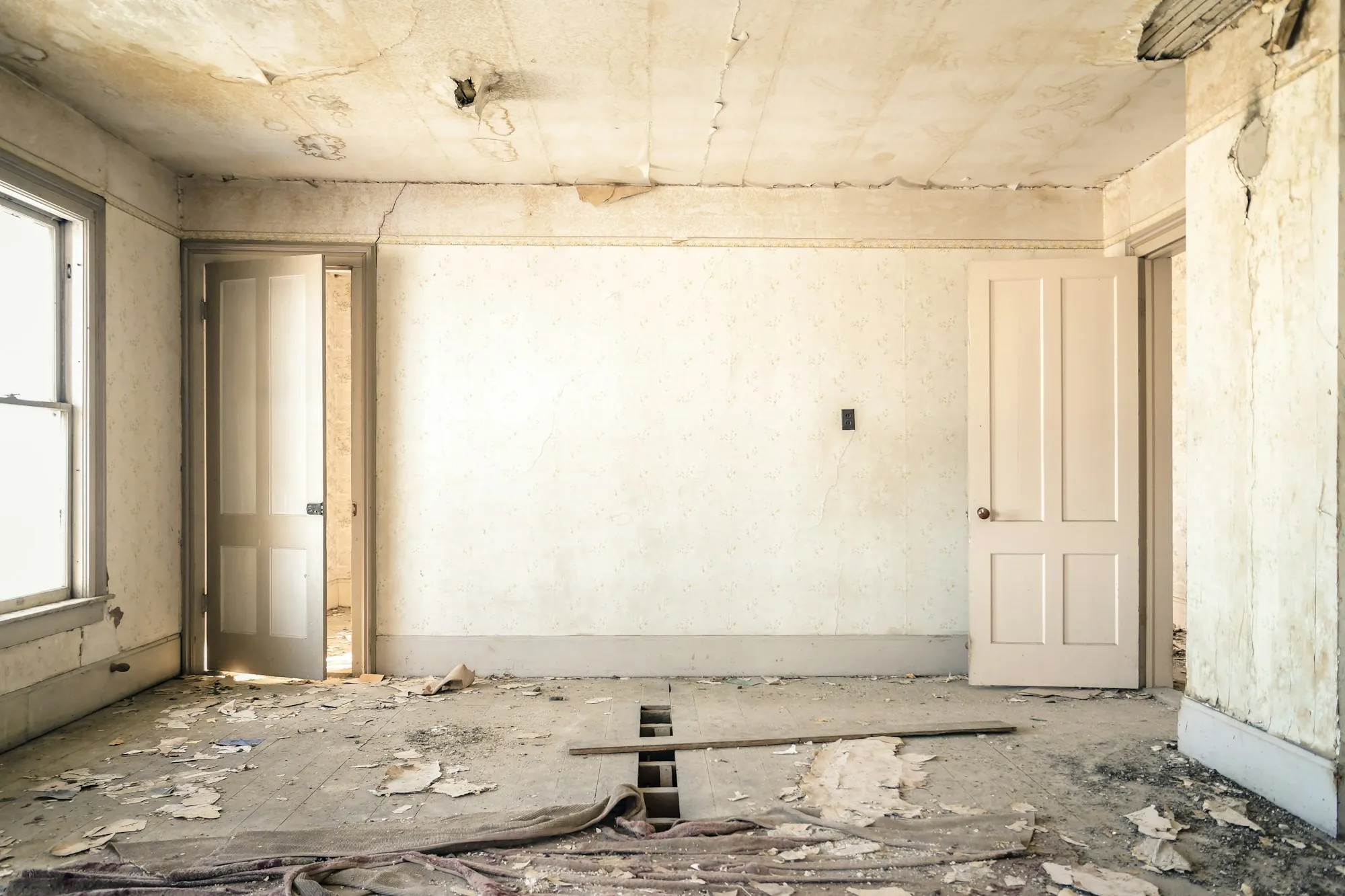 Gutted room with bare plaster walls and an open ceiling ready for renovation